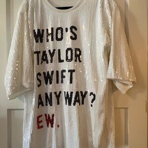 White sequin tunic with bold black text reading "WHO'S TAYLOR SWIFT ANYWAY